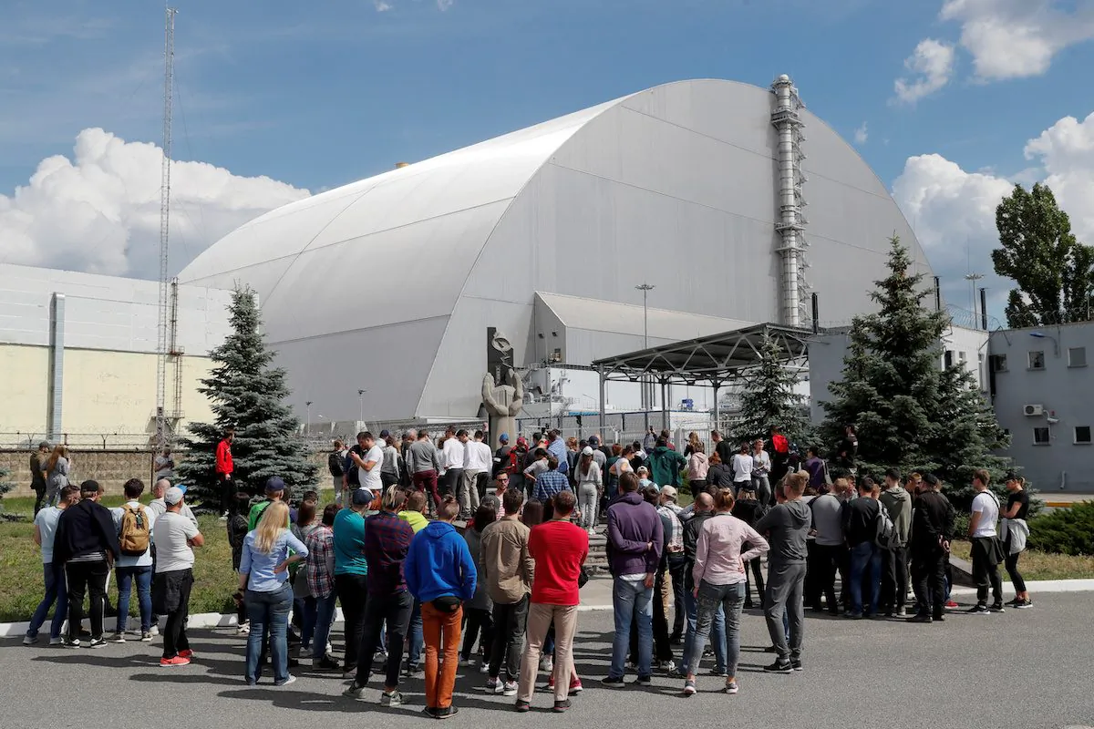 Visitors stand outside the New Safe Confinement (NSC) structure over the old sarcophagus covering the damaged fourth reactor at the Chernobyl Nuclear Power Plant, in Chernobyl, Ukraine June 2, 2019. (Valentyn Ogirenko/Reuters)