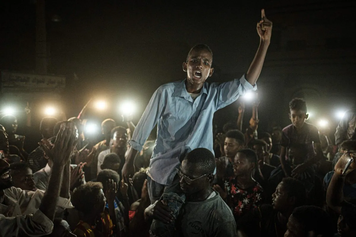 People chant slogans as a young man recites a poem, illuminated by mobile phones, before the opposition's direct dialog with people in Khartoum, Sudan on June 19, 2019.(YASUYOSHI CHIBA/AFP/Getty Images)