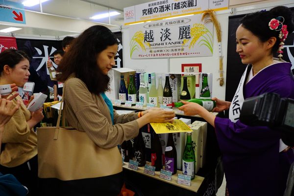 woman enjoys a tasting of sake at japanese sake fair