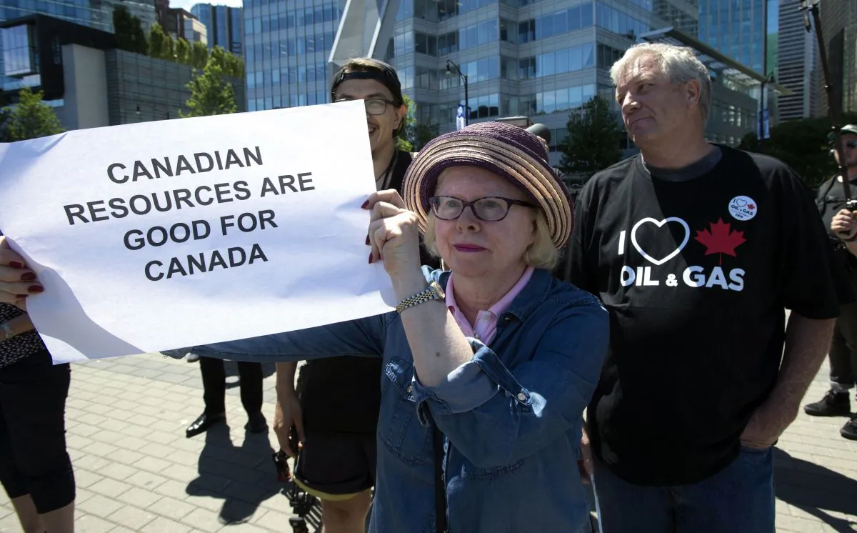 A woman holds up a sign during a pro-pipeline gathering in downtown Vancouver on June 18, 2019. With the re-approval of the Trans Mountain pipeline expansion, a number of realistic proposals for Indigenous ownership of the project are in play. (THE CANADIAN PRESS/Jonathan Hayward)