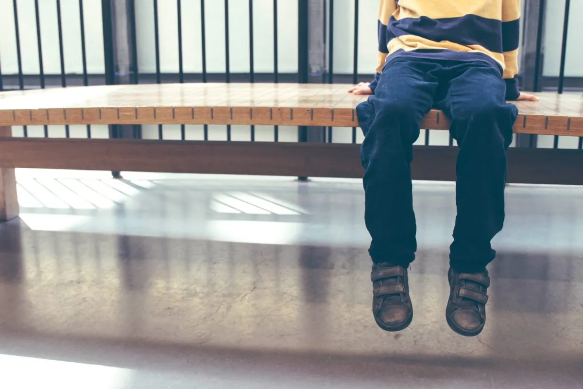Legs of a boy resting on bench. (Stock/Michał Parzuchowski/Unsplash)