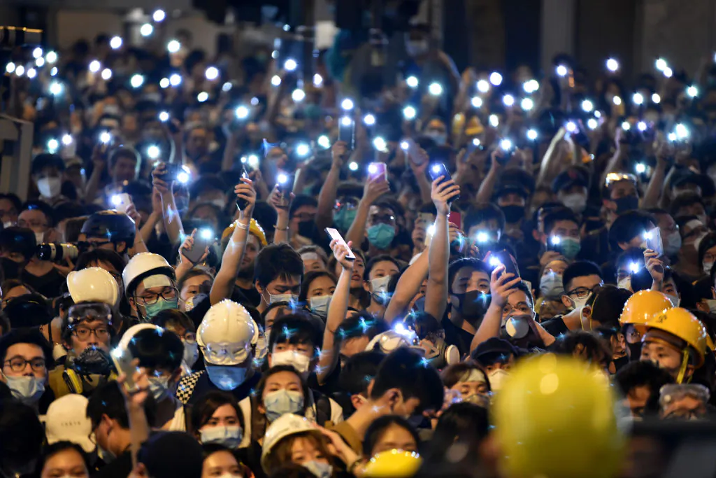 Protesters hold up their mobile phones as they gather outside the police headquarters in Hong Kong on June 21, 2019. (Hector Retamal/AFP/Getty Images)