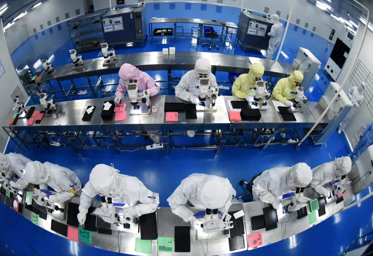 Employees work on a production line manufacturing camera lenses for cellphones at a factory in Lianyungang, Jiangsu Province, China on April 30, 2019. (China Daily via Reuters)
