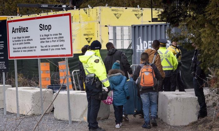 A family, claiming to be from Columbia, is arrested by RCMP officers as they cross the border into Canada from the United States as asylum seekers on April 18, 2018 near Champlain, New York. (Paul Chiasson/The Canadian Press)