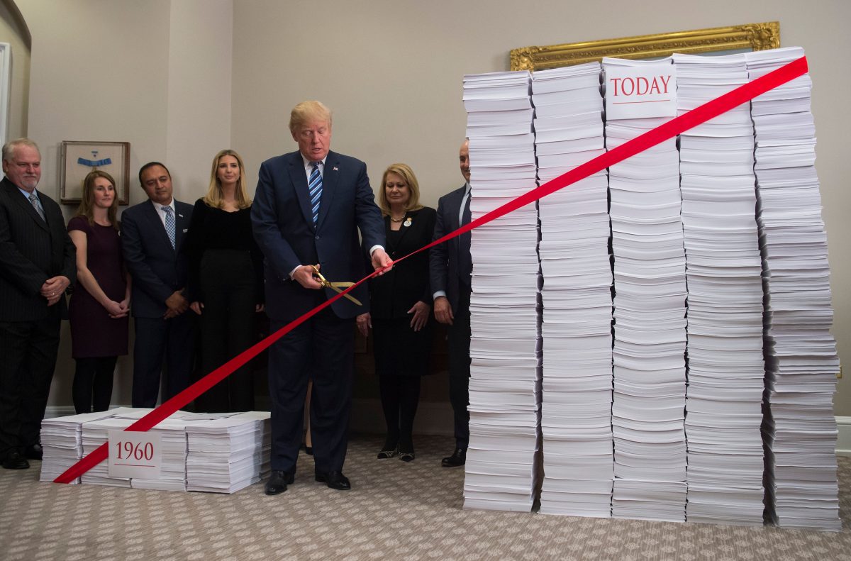 Trump uses gold scissors to cut a red tape