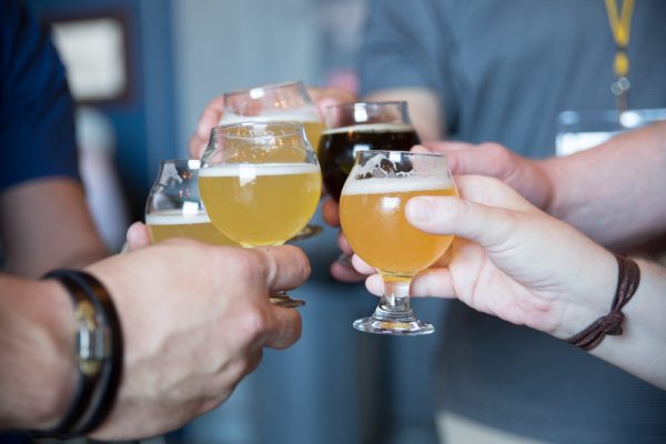 friends hold four glasses of beer samples