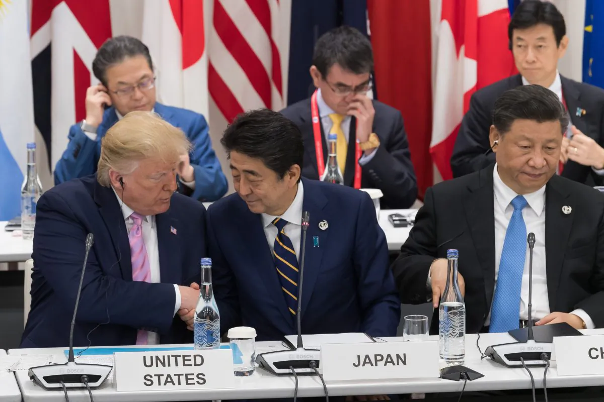 US President Donald Trump (L) shakes hands with Japan's Prime Minister Shinzo Abe (C) as they sit beside China's President Xi Jinping as they attend a meeting on the digital economy at the G20 Summit in Osaka on June 28, 2019. (JACQUES WITT/AFP/Getty Images)