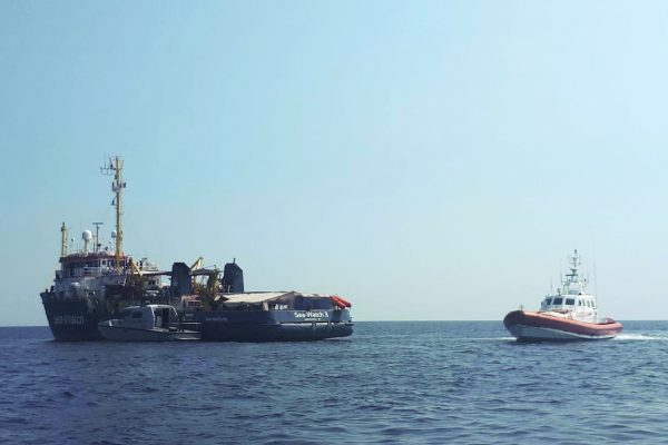 An Italian Coast Guard boat patrols next to the Sea-Watch 3 vessel
