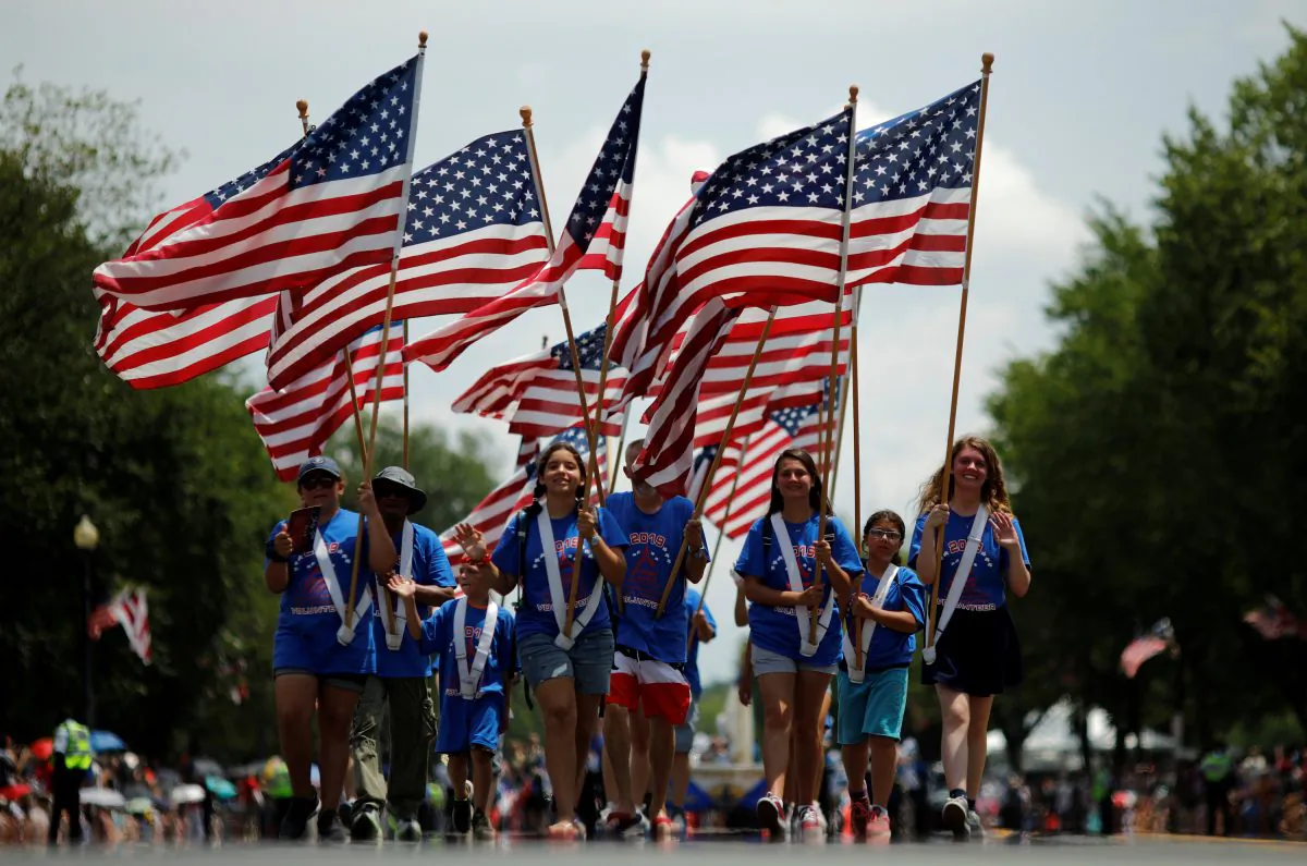 People carry U.S. flags as they take part in a parade during Fourth of July Independence Day celebrations in Washington on July 4, 2019. (Carlos Barria/Reuters)
