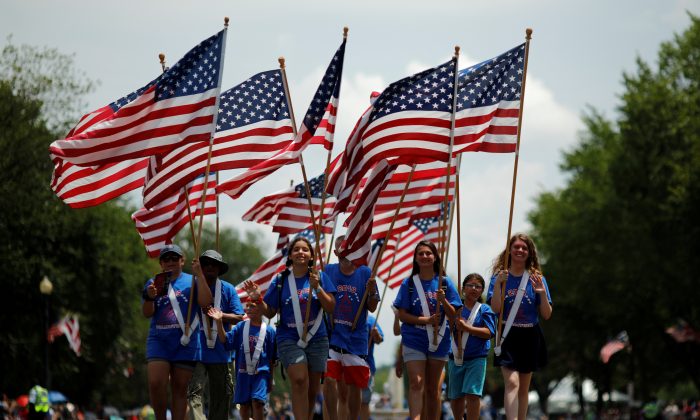 People carry U.S. flags as they take part in a parade during Fourth of July Independence Day celebrations in Washington on July 4, 2019. (REUTERS/Carlos Barria)