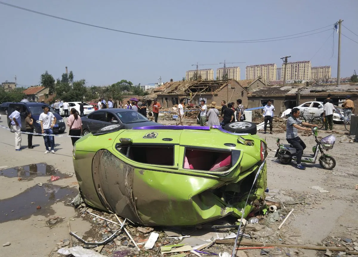 Residents past by an overturned car in the aftermath of a tornado in Kaiyuan in northeastern China's Liaoning Province on July 4, 2019. A tornado blew through the city in northeast China, damaging factories and buildings, killing some people and injuring others, state media reported. (Chinatopix Via AP)