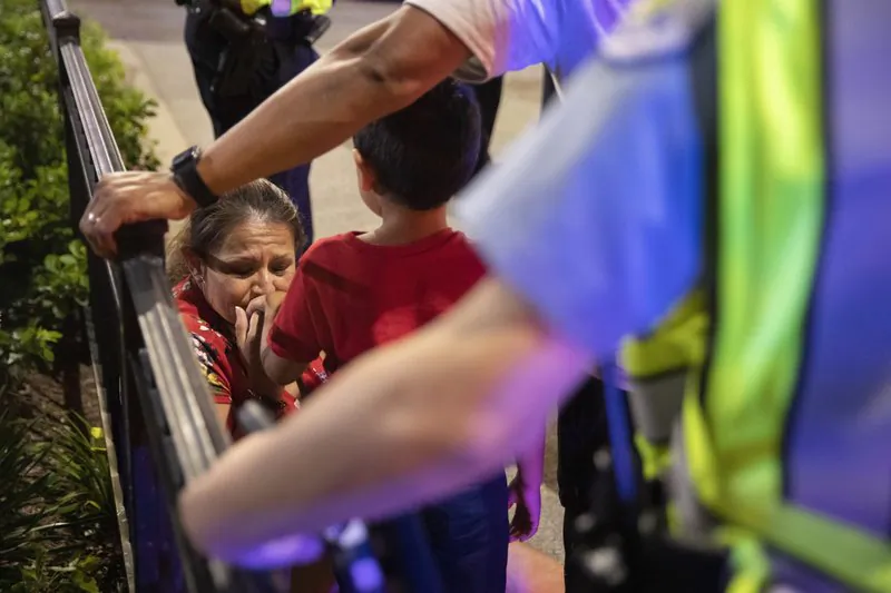 Chicago Police Department (CPD) officers stand guard while a woman relieves her son who had panicked after reports of stabbings and threatening injuries after the 4th of July celebrations at Chicago's Navy Pier. (Amr Alfiky/Photo via AP)