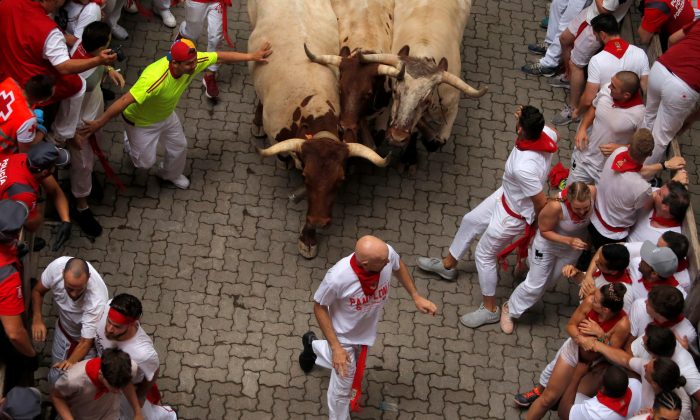 Revelers sprint in front of steers during the first running of the bulls at the San Fermin festival in Pamplona, Spain, on July 7, 2019. (Reuters/Jon Nazca)