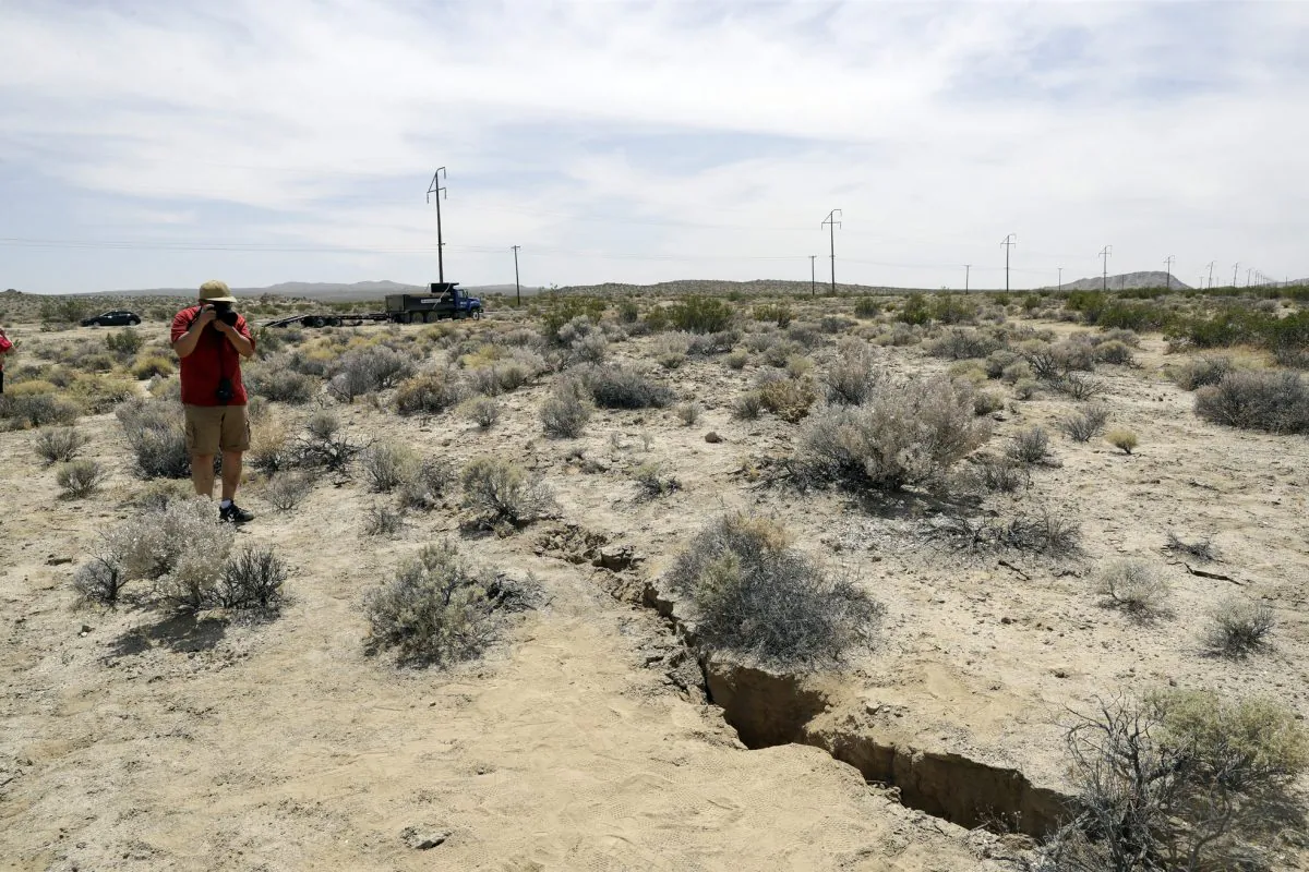 A visitor takes a photo of a crack on the ground following recent earthquakes outside of Ridgecrest, Calif. on July 7, 2019.  (Marcio Jose Sanchez/AP Photo)