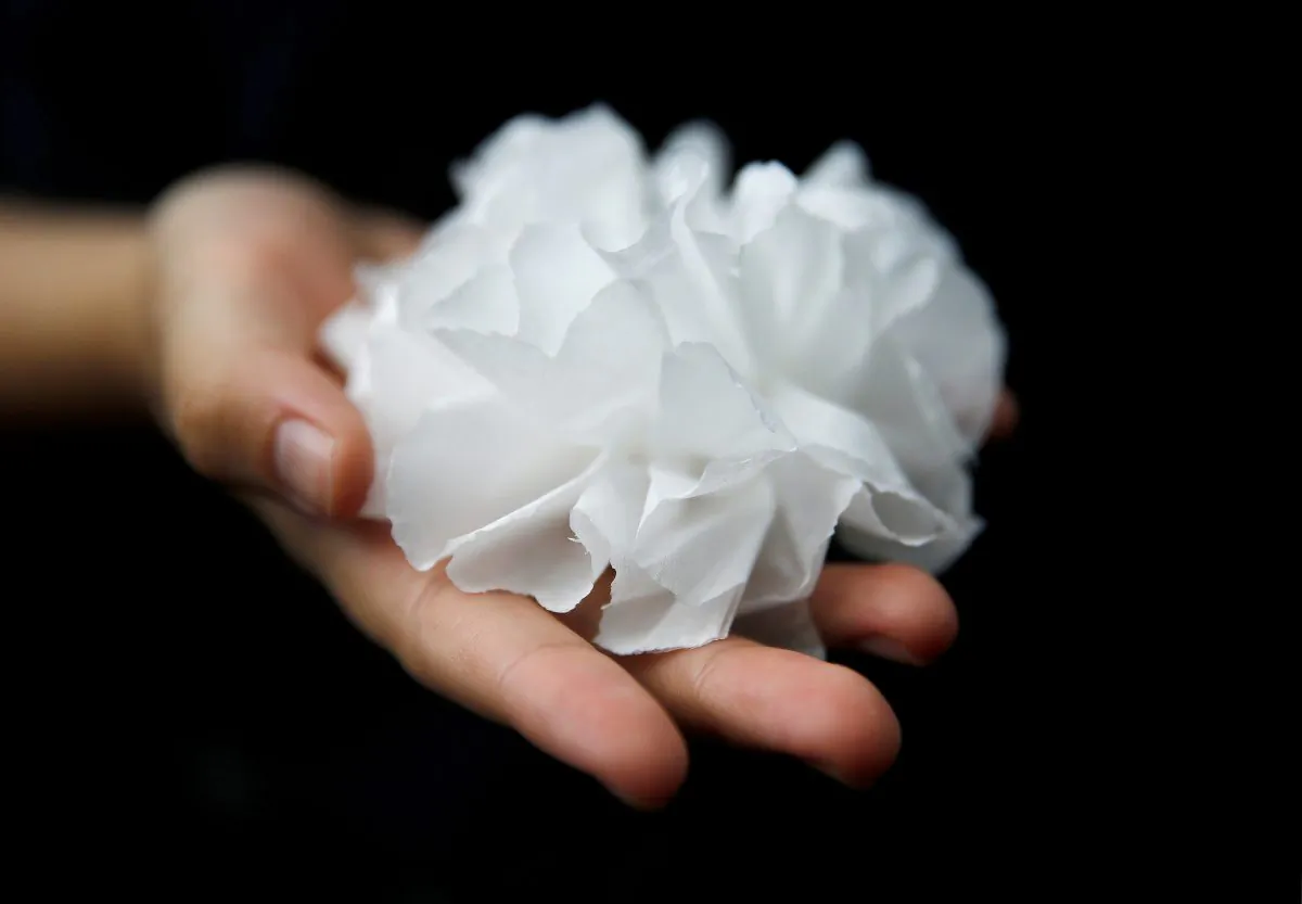 A protester offers a paper flower to pay honor to a man, who died after falling from a scaffolding at the Pacific Place complex while protesting, during a demonstration demanding Hong Kong's leaders to step down and withdraw the extradition bill, in Hong Kong, China, on June 16, 2019. (Thomas Peter/Reuters)