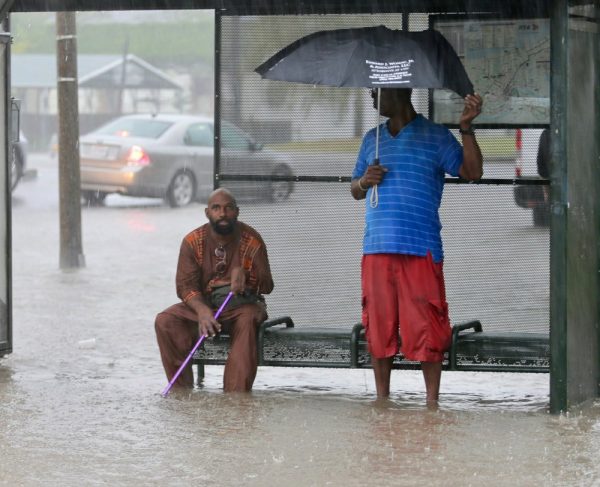 Residents sit under a bus shelter