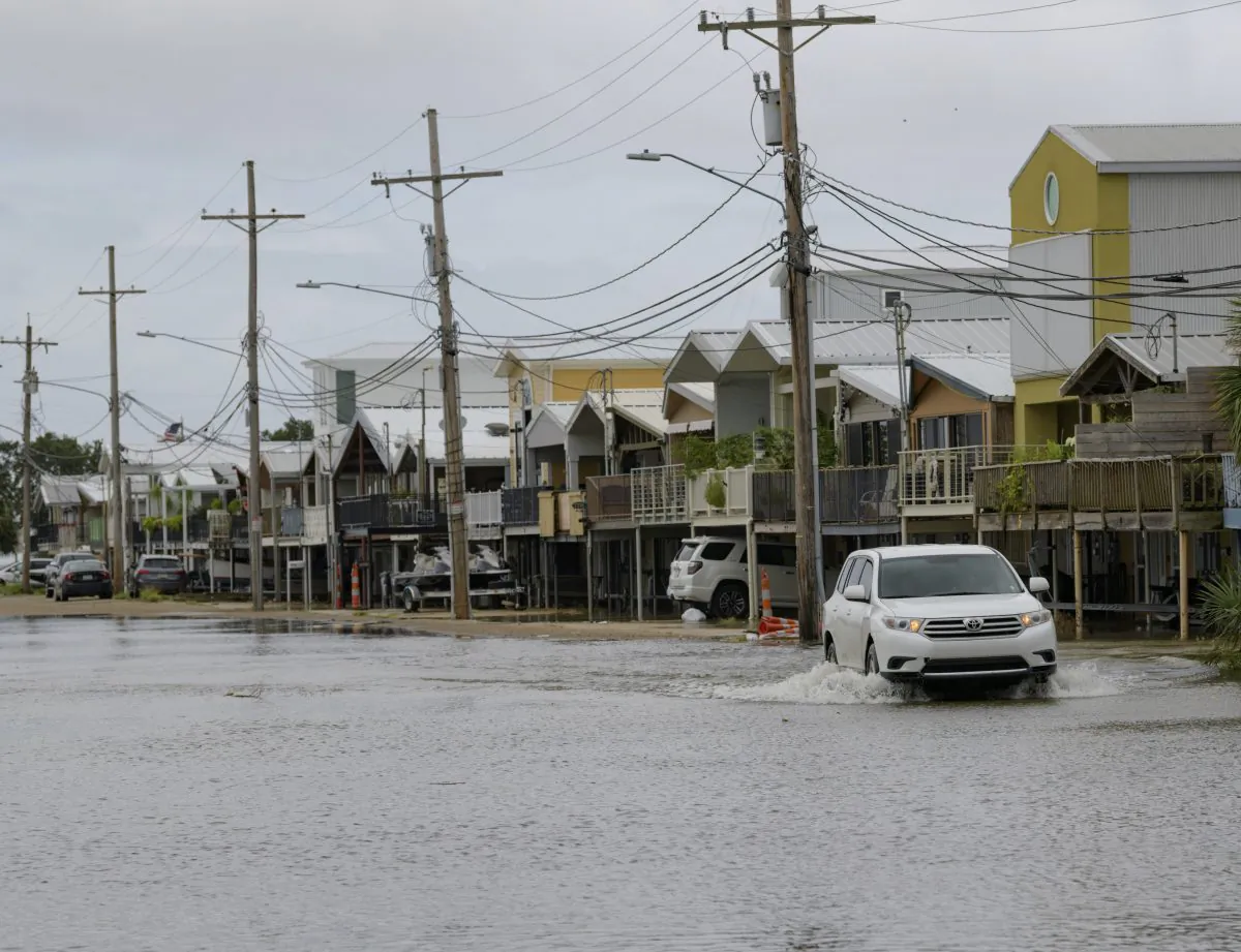An SUV travels down Breakwater Drive in New Orleans, La., July 12, 2019, near the Orleans Marina as water moves in from Lake Pontchartrain from the storm surge from Tropical Storm Barry in the Gulf of Mexico. The area is behind a flood wall that protects the rest of the city. (AP Photo/Matthew Hinton)