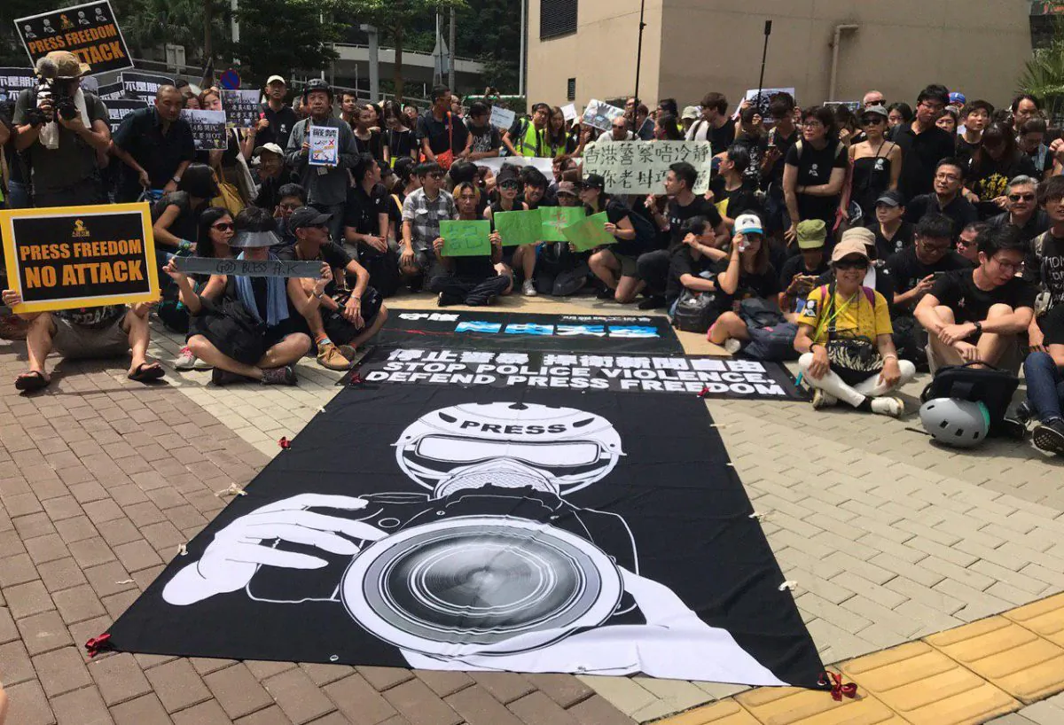 A giant poster reads “Stop Police Violence, Defend Press Freedom” at Harcourt Garden on July 14, 2019. (Lin Yi/The Epoch Times)