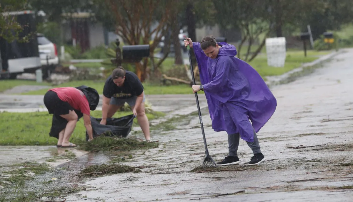 Residents clean up pine branches deposited from Tropical Storm Barry, in front of their houses in Morgan City, La., on July 13, 2019. (Rogelio V. Solis/AP Photo)