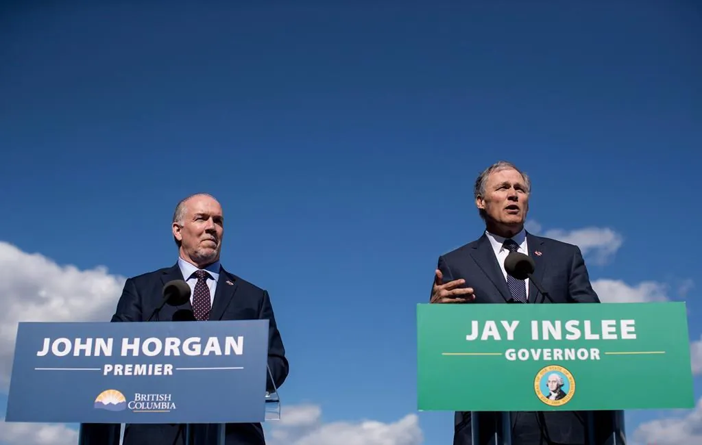 British Columbia Premier John Horgan, left, listens as Washington State Gov. Jay Inslee speaks during a news conference about high speed rail, in Vancouver, B.C., on March 16, 2018. (Darryl Dyck/The Canadian Press)