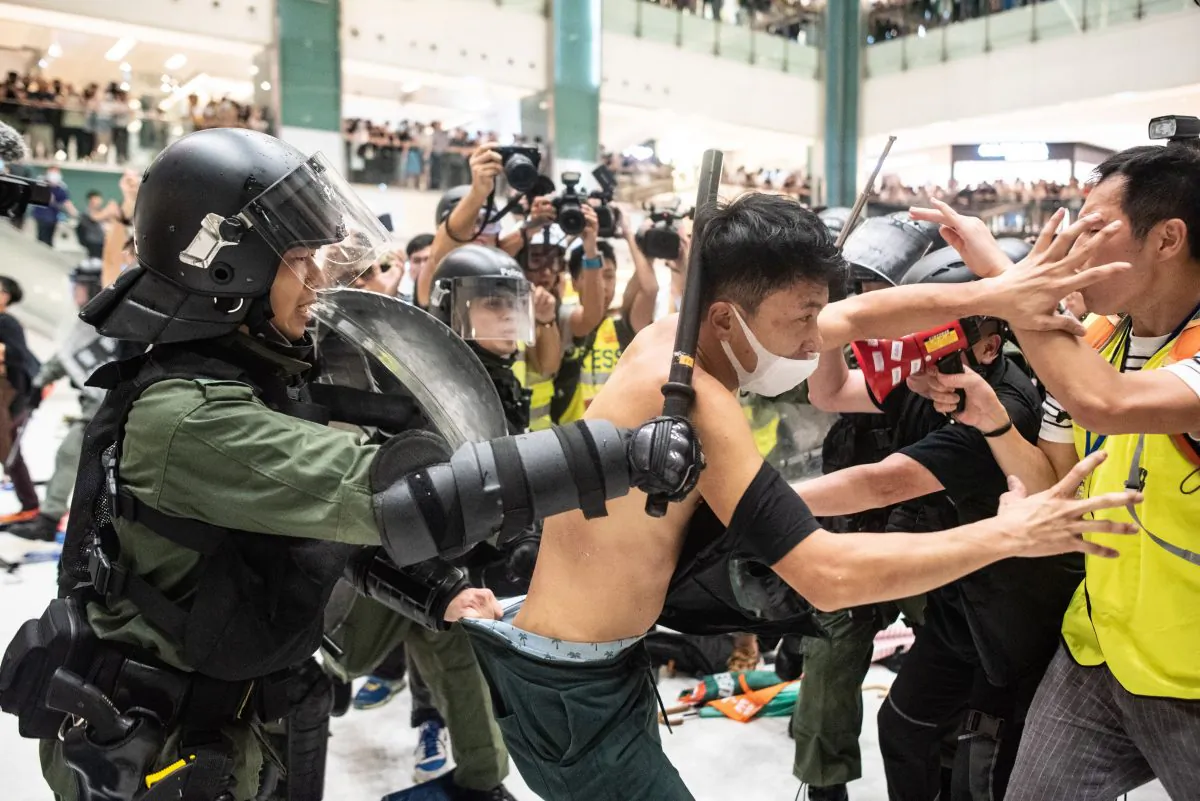 Police officers tear the shirt of a protester during a clash inside a shopping arcade after a rally against a controversial extradition bill in Sha Tin district of Hong Kong on July 14, 2019. (PHILIP FONG/AFP/Getty Images)