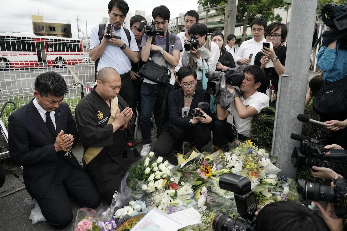 Japanese Diet member, Kenta Izumi (L), and Buddhist monk, Matsumoto Genkun, pay respects at a makeshift memorial site in front of burned Kyoto Animation Studio, in Kyoto, Japan, on July 19, 2019. (Jae C. Hong/AP Photo)