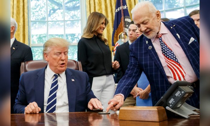 President Donald Trump receives a gift from Apollo 11 astronaut Buzz Aldrin, with first lady Melania Trump, during a photo opportunity commemorating the 50th anniversary of the Apollo 11 moon landing in the Oval Office of the White House, Friday, July 19, 2019, in Washington. (AP Photo/Alex Brandon)