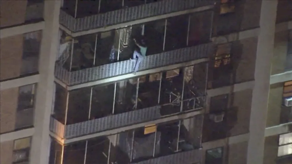 A man scales a burning 19-story building that had caught on fire on July 18, 2019. (WPVI-TV via AP)