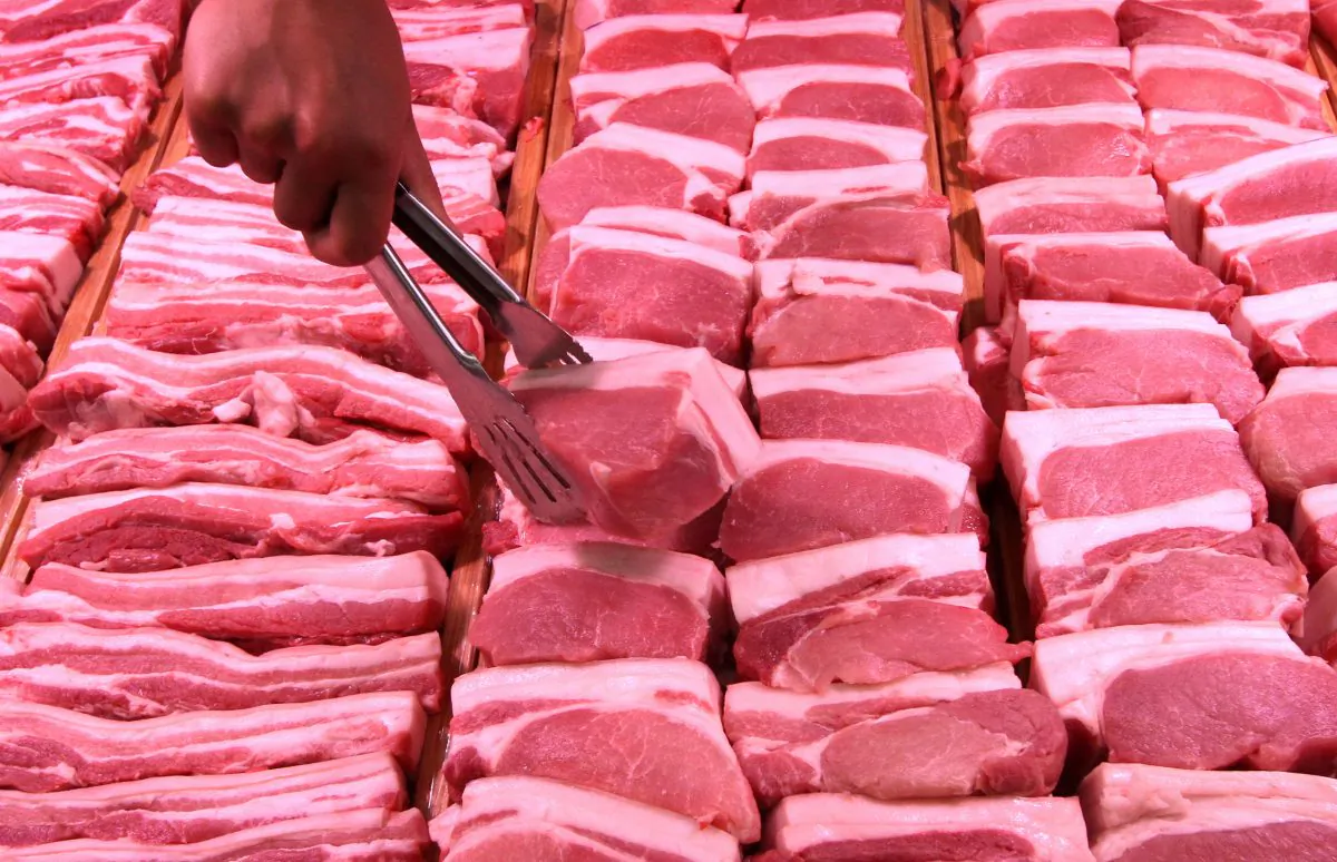 A staff member lifts a pork slice with tongs at a supermarket in Handan, Hebei Province, China, on June 12, 2019. (Reuters)