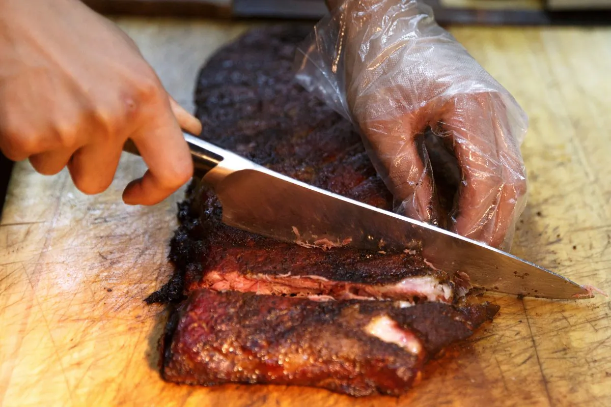 A chef cuts U.S. imported pork ribs that were smoked at the Beijing barbeque restaurant Home Plate in China that specializes in meat from the U.S., June 29, 2018. (Thomas Peter/Reuters)