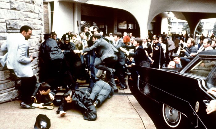 Police and Secret Service agents reacting during the assassination attempt on then US president Ronald Reagan, after a conference outside the Hilton Hotel in Washington, D.C. on March 30, 1981. (just behind the car).  Reagan was hit in the chest and was hospitalized for 12 days. Hinckley was aquitted 21 June 1982 after a jury found him mentally unstable. (Mike Evens/AFP/Getty Images)