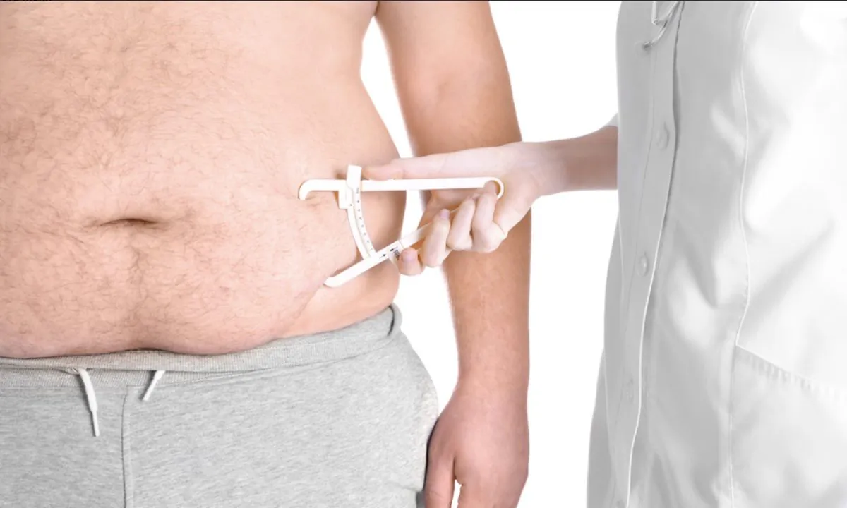 Stock image of a doctor measuring fat on a man's stomach. (Africa Studio/Shutterstock)