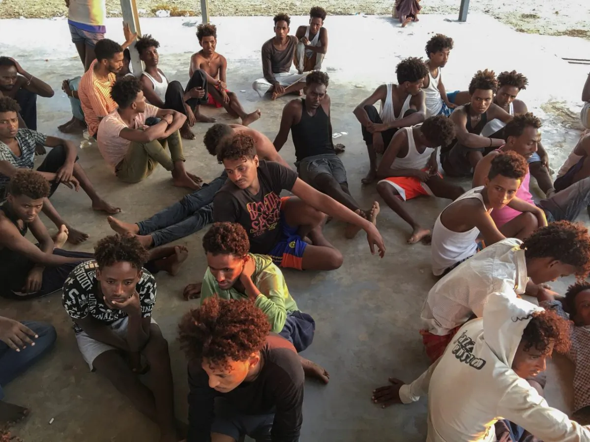 Rescued migrants sit on a coast some 60 miles east of Tripoli, Libya, on  July 25, 2019. (Hazem Ahmed/AP Photo)