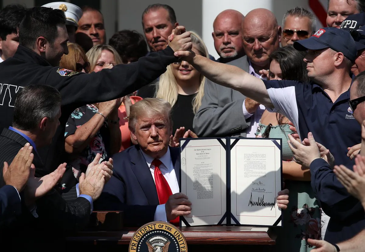 As first responders and their families celebrate, President Donald Trump shows his signature on H.R. 1327, an act to permanently authorize the Sept. 11 victim compensation fund, in the Rose Garden of the White House in Washington on July 29, 2019. (Win McNamee/Getty Images)
