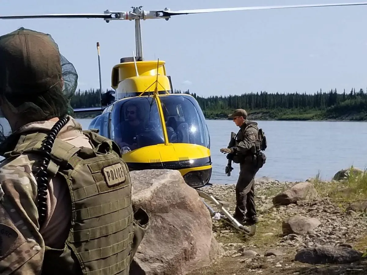 RCMP officers work near a helicopter responsible for aerial search. The force has announced that they will withdraw their resources from York Landing, Manitoba, after an unsuccessful attempt to locate two B.C. murder suspects. (Royal Canadian Mounted Police)