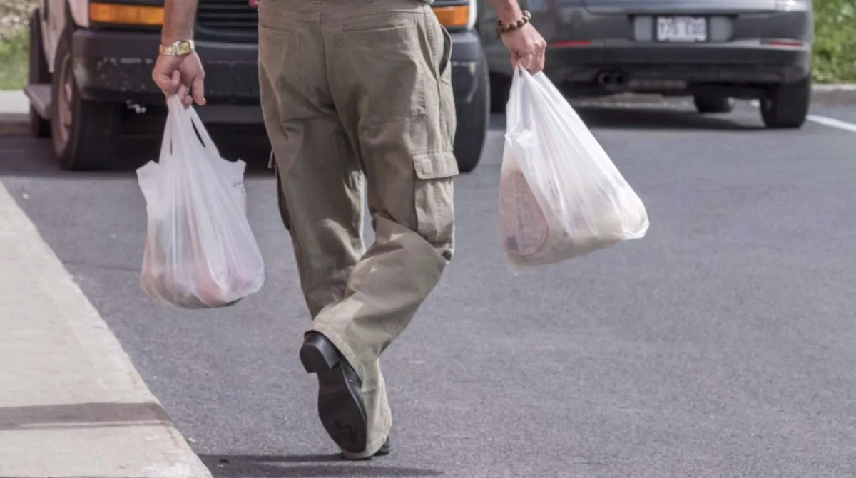 A shopper leaves a grocery store carrying his groceries in plastic bags in Brossard, Que., on Aug. 30, 2016. Shoppers at Sobeys Inc. grocery stores will soon need to bring their own bags to pack their purchases or lug them home in paper bags as the chain moves to phase out plastic bags by February 2020. (Paul Chiasson/The Canadian Press)