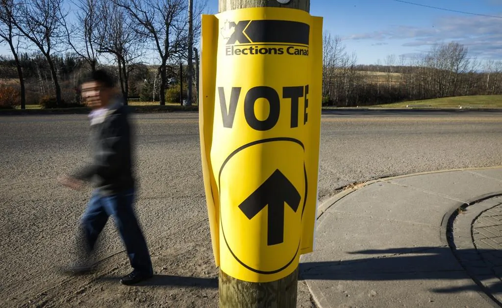 A voter walks past a sign directing voters to a polling station for the Canadian federal election in Cremona, AB., Oct. 19, 2015. (The Canadian Press/Jeff McIntosh)
