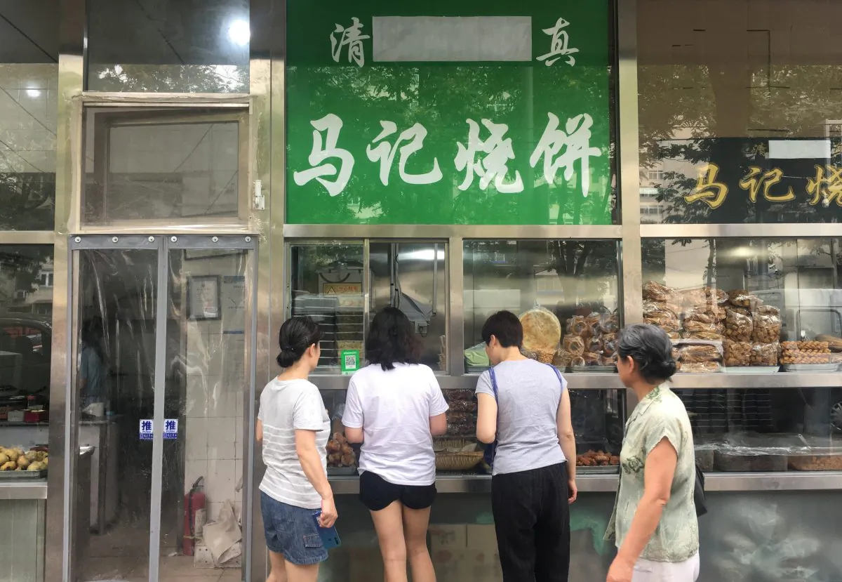 The Arabic script on the signboard of a halal food store is seen covered, at Niujie area in Beijing on July 19, 2019. (Reuters)