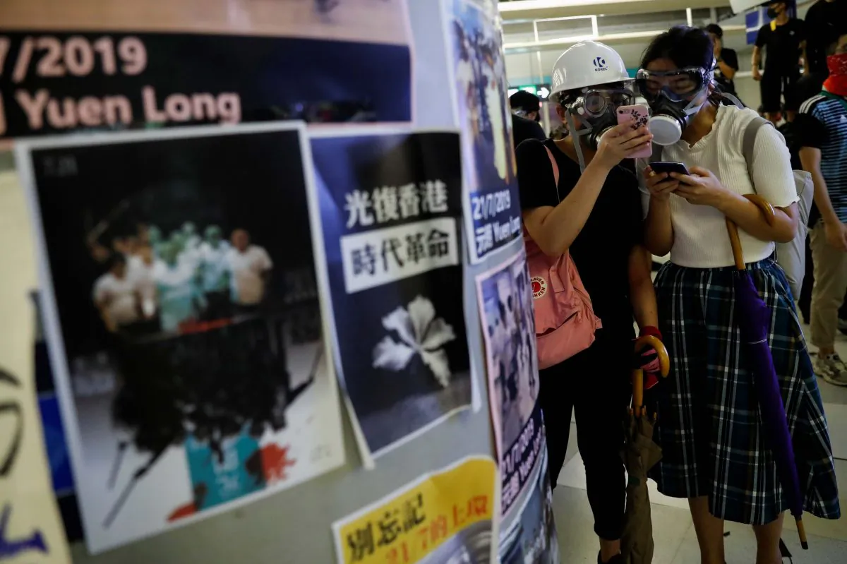 Protesters check their phones as they take part in a protest inside the Yuen Long MTR station, the scene of an attack by suspected triad gang members a month ago, in Yuen Long, New Territories, Hong Kong, China on Aug. 21, 2019. (Tyrone Siu/Reuters)