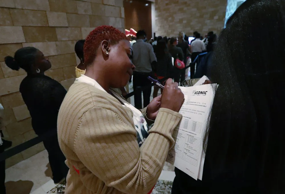 Job applicant Esta Williams (C), uses Tracy Simeton's back to fill out a questionnaire as they wait in line at the Seminole Hard Rock Hotel & Casino Hollywood during a job fair in Hollywood, Fla., on June 4, 2019. (Wilfredo Lee/File Photo via AP)