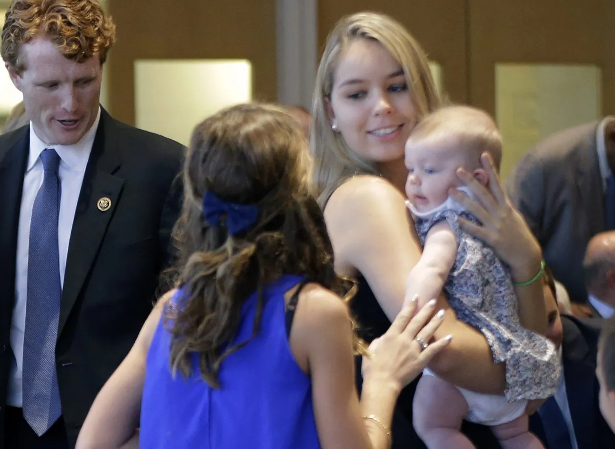 In this Sept. 20, 2016, photo, Saoirse Kennedy Hill, right, granddaughter of Ethel Kennedy and her late husband Robert F. Kennedy, holds a relative's baby before a ceremony for naming the Robert Kennedy Navy Ship at the John F. Kennedy Presidential Library, in Boston. (AP Photo/Elise Amendola)