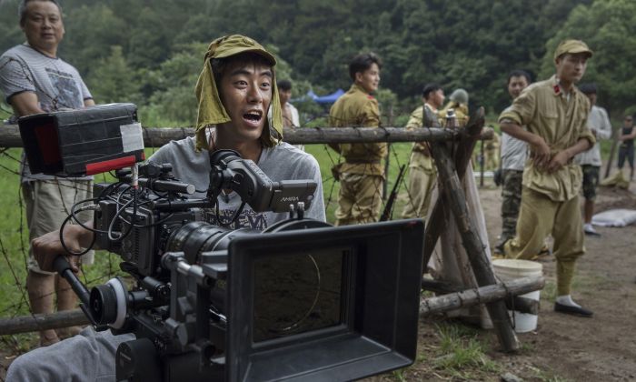 A Chinese cinematographer wears a Japanese army hat during the filming of the series “The Last Noble,” set during the second Sino-Japanese War in Fangyan, China, on Aug. 13, 2015.  (Kevin Frayer/Getty Images)