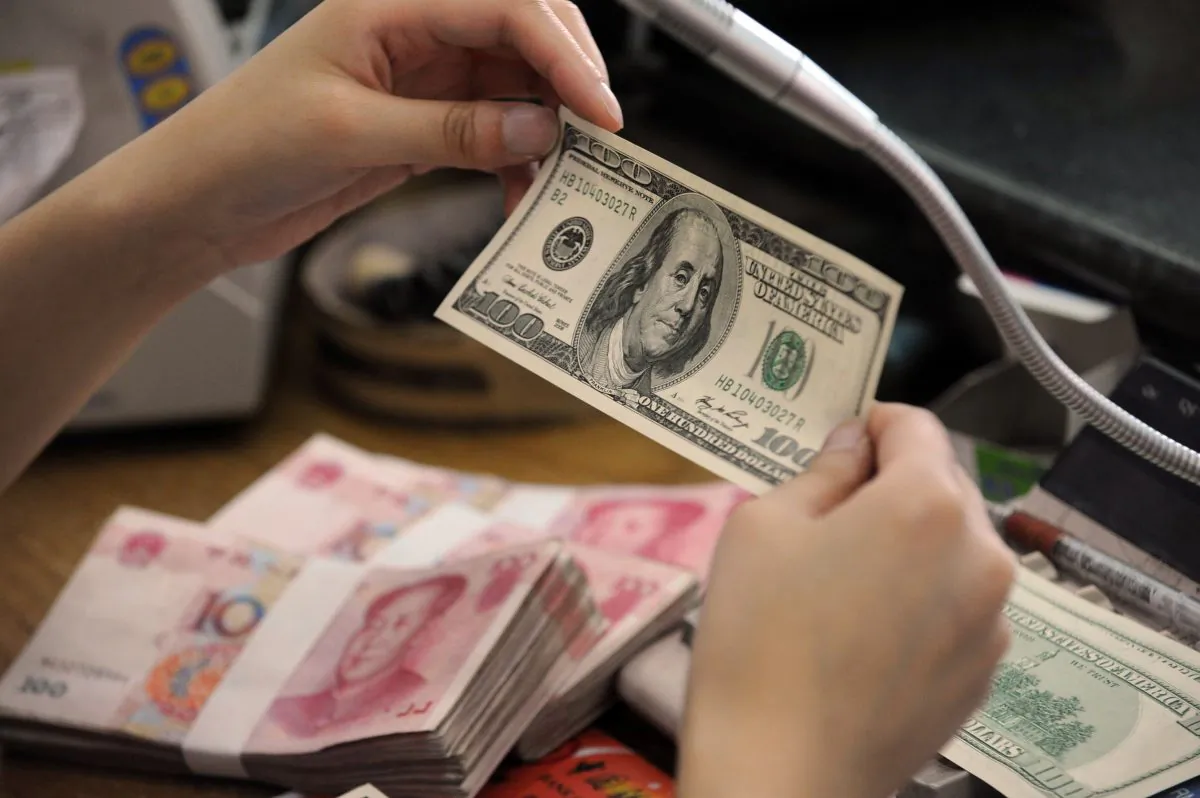 A Chinese bank worker checks a U.S. 100 dollar bill together with stacks of 100 yuan notes at a bank counter in Hefei City, Anhui Province, China, on Sept. 30, 2010. (STR/AFP/Getty Images)