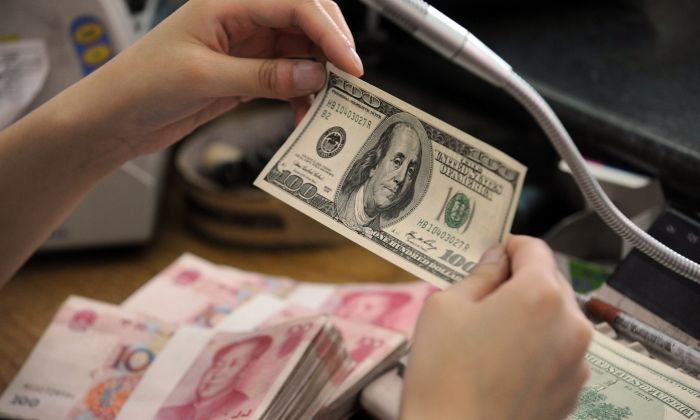 A Chinese bank worker checks a U.S. 100-dollar bill together with stacks of 100-yuan notes at a bank counter in Hefei City, Anhui Province, China, on Sept. 30, 2010. (STR/AFP/Getty Images)