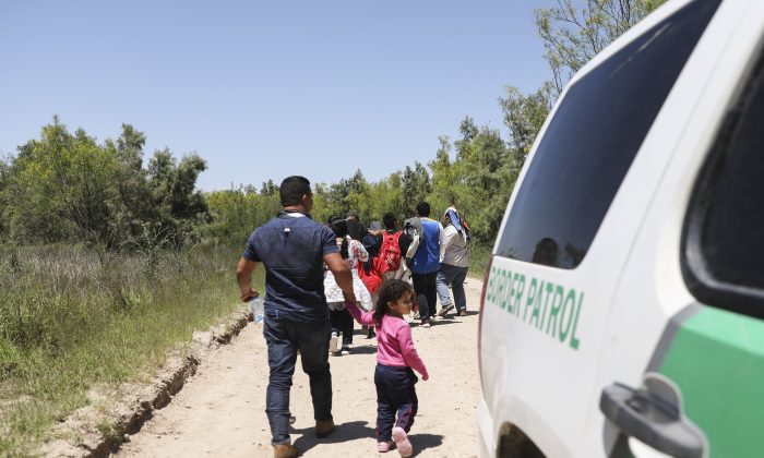 A group of illegal aliens walk up the road after crossing the Rio Grande from Mexico, near McAllen, Texas, on April 18, 2019. (Charlotte Cuthbertson/The Epoch Times)
