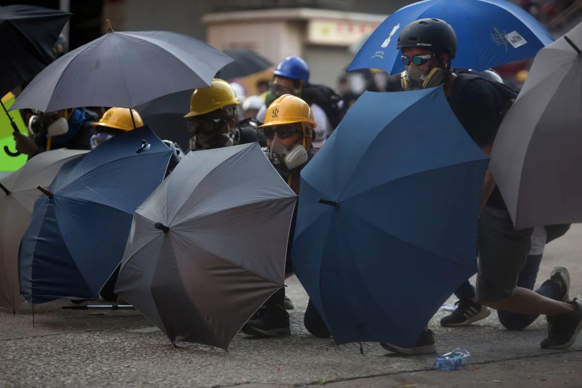 Protesters take shelter behind umbrellas after police fired tear gas in Wong Tai Sin during a general strike in Hong Kong on Aug. 5, 2019. (Isaac Lawrence/AFP/Getty Images)