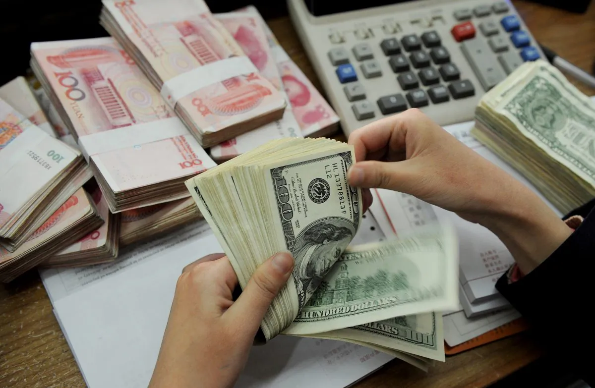 A bank teller counting stacks of US dollars and Chinese 100-yuan notes at a bank in Hefei, east China's Anhui province on Jan. 16, 2011. (STR/AFP/Getty Images)