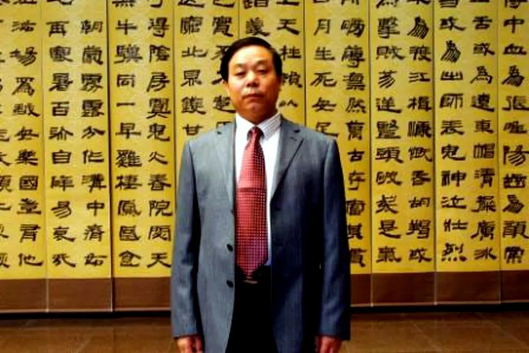 Liu Xitong in front of one of his calligraphy works at his exhibit. Loitering among the attendees were several plainclothes police officers. (Minghui.org)