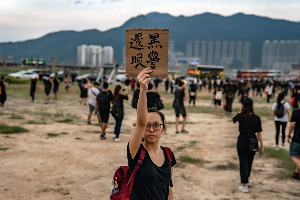 A protester holds up a placard which translates as 'policeman pay the eye back' outside the Hong Kong International Airport as protesters retreat during a demonstration in Hong Kong on Aug. 12, 2019. (Anthony Kwan/Getty Images)