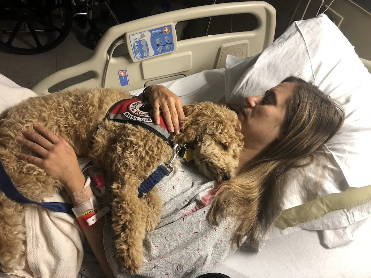 Katie Harris in the hospital with her service dog Moxie. (Courtesy of Katie Harris)